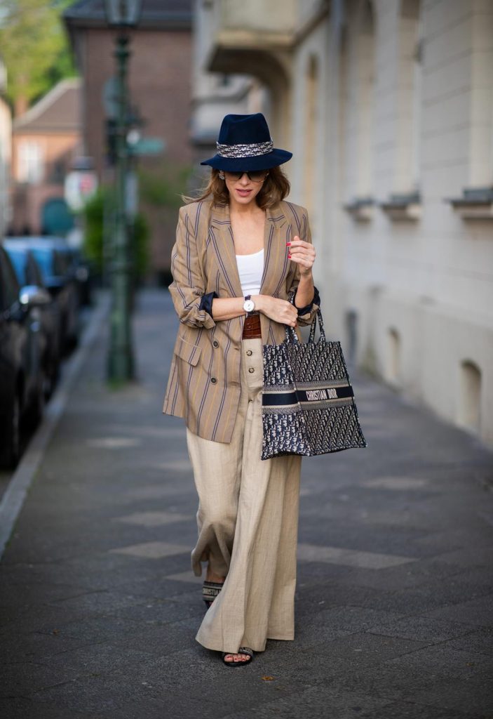 Alexandra Lapp is seen wearing a beige brown long striped blazer from Zara, white tank top from H&M, waisted belt from Max Mara, high waisted wide leg pants from Staud, Dior Book Tote Dior Oblique bag and a Dior foulard on a blue Borsalino hat on May 04, 2019 in Duesseldorf, Germany. (Photo by Christian Vierig/Getty Images)