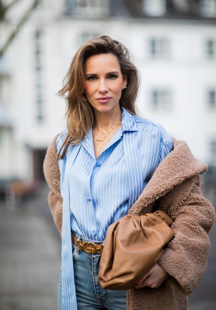 DUESSELDORF, GERMANY - DECEMBER 10: Alexandra Lapp is seen wearing brown Zara teddy coat, oversized blue striped button shirt Balenciaga, brown Gucci belt, light blue ripped denim jeans Celine, brown Pouch bag Bottega Veneta, brown Jimmy Choo boots with snake print on December 10, 2019 in Duesseldorf, Germany. 