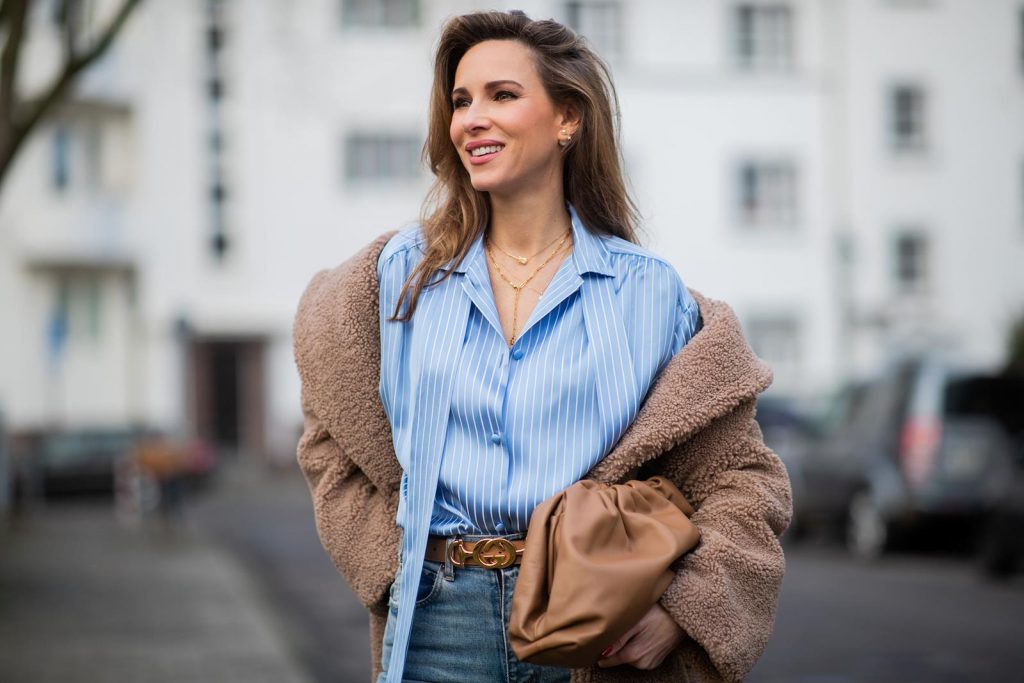 DUESSELDORF, GERMANY - DECEMBER 10: Alexandra Lapp is seen wearing brown Zara teddy coat, oversized blue striped button shirt Balenciaga, brown Gucci belt, light blue ripped denim jeans Celine, brown Pouch bag Bottega Veneta, brown Jimmy Choo boots with snake print on December 10, 2019 in Duesseldorf, Germany. 