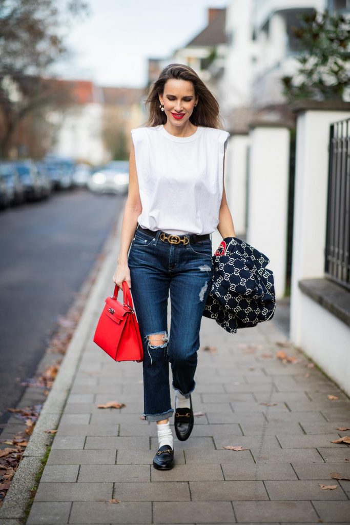 college look, Gucci, AG Denim, Adriano Goldschmied, Gucci loafers, Falke, Dior, The Frankie Shop, Hermes, Kelly bag DUESSELDORF, GERMANY - DECEMBER 11: Alexandra Lapp is seen wearing a college look, dark denim blue jeans AG Jeans, white sleeveless muscle tshirt with padded shoulders The Frankie Shop, Gucci GG horsebit leather belt, Gucci college jacket with logo print, red Hermes Kelly bag on December 11, 2019 in Duesseldorf, Germany. (Photo by Christian Vierig/Getty Images)