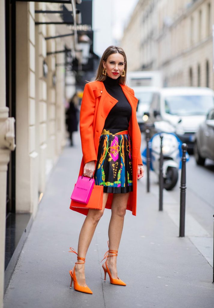 Alexandra Lapp, Givenchy, Versace, Dorothee Schumacher, slingback pumps, The Attico, Balenciaga, Medea, Paris Fashion Week, Womenswear Fall/Winter 2020/2021 PARIS, FRANCE - FEBRUARY 26: Alexandra Lapp is seen wearing a Givenchy coat in orange, pleated silk skirt from Versace, turtleneck pullover in black from Dorothee Schumacher, slingback pumps in orange from The Attico, Balenciaga Tote Shopping Phone bag, Medea Vinile Short bag during Paris Fashion Week - Womenswear Fall/Winter 2020/2021 : Day Three on February 26, 2020 in Paris, France.