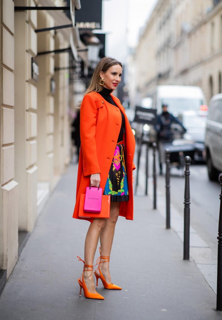 Alexandra Lapp, Givenchy, Versace, Dorothee Schumacher, slingback pumps, The Attico, Balenciaga, Medea, Paris Fashion Week, Womenswear Fall/Winter 2020/2021 PARIS, FRANCE - FEBRUARY 26: Alexandra Lapp is seen wearing a Givenchy coat in orange, pleated silk skirt from Versace, turtleneck pullover in black from Dorothee Schumacher, slingback pumps in orange from The Attico, Balenciaga Tote Shopping Phone bag, Medea Vinile Short bag during Paris Fashion Week - Womenswear Fall/Winter 2020/2021 : Day Three on February 26, 2020 in Paris, France.