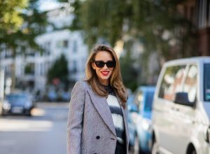 Alexandra Lapp is seen wearing Alexander McQueen coat with prince of wales check, SAINT LAURENT striped mohair-blend sweater, SAINT LAURENT high waist pants in black, CELINE Bucket Crécy bag in black and Isabel Marant pointed-toe knee-high boots in black.