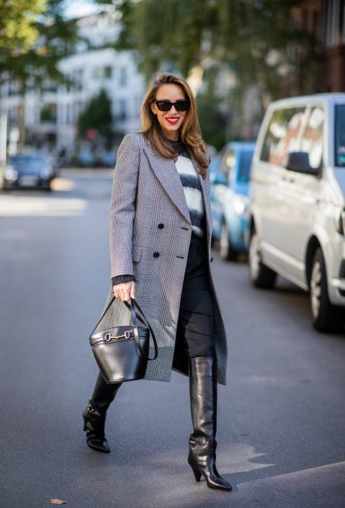 Alexandra Lapp is seen wearing Alexander McQueen coat with prince of wales check, SAINT LAURENT striped mohair-blend sweater, SAINT LAURENT high waist pants in black, CELINE Bucket Crécy bag in black and Isabel Marant pointed-toe knee-high boots in black.