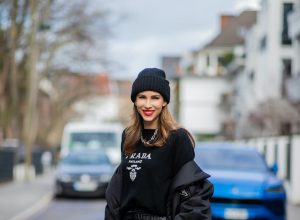 Alexandra Lapp is seen wearing PRADA Piumino nylon coat in black, PRADA knitted logo jumper in black, TIFFANY&CO. City HardWear necklace in sterling silver, SET leather joggers in black, XX knitted beanie, HERMÈS Kelly 28 bag in black, CHRISTIAN LOUBOUTIN So Kate pumps in black.