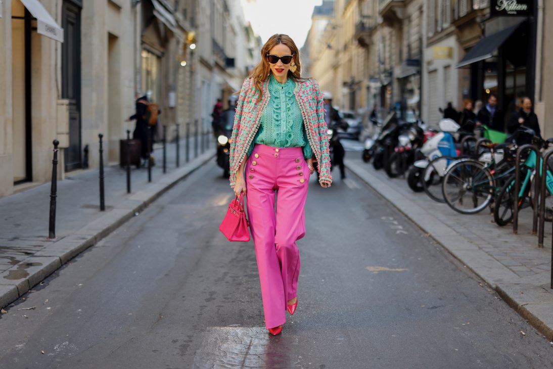 Alexandra Lapp is seen wearing colorful look during Paris Fashion Week by MAISON COMMON tweed jacket in green and pink, MAISON COMMON ruffles blouse in green, MAISON COMMON flared trousers in pink, ZARA heart ear rings in gold, HERMES Kelly bag in pink, and PRADA pumps in pink.